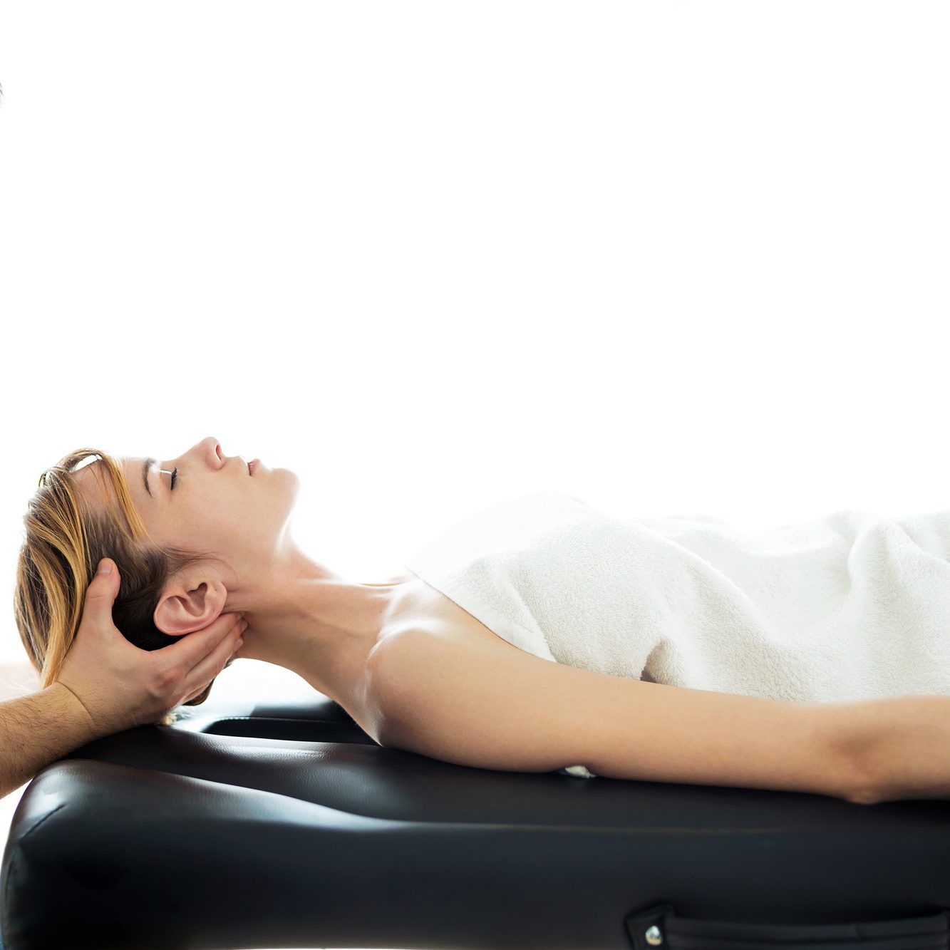 Young physiotherapist doing a neck treatment to the patient in a physiotherapy room.